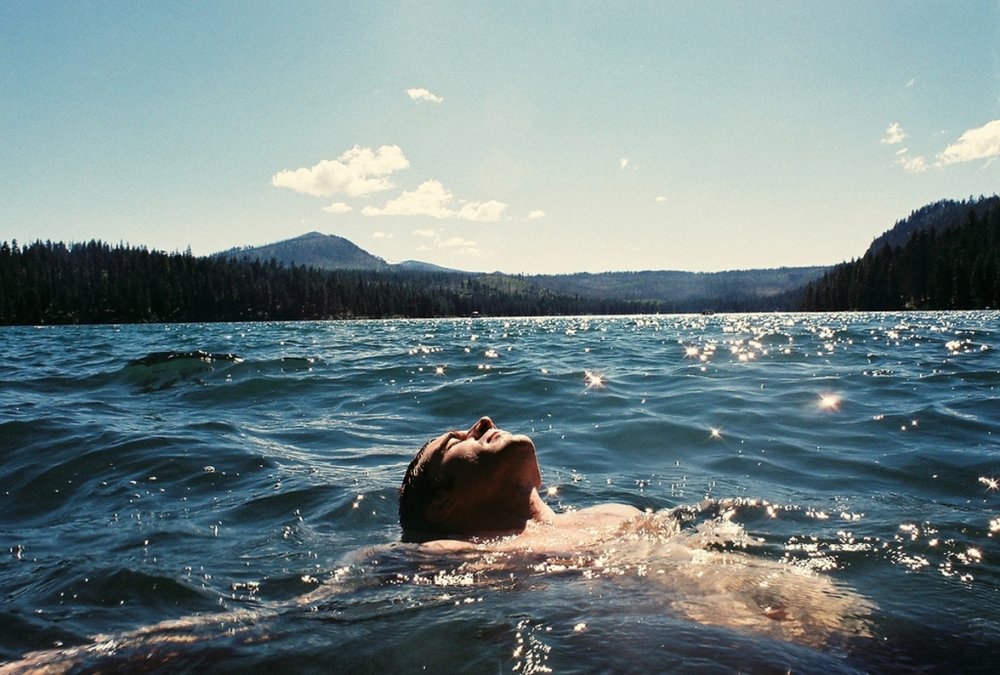 Человек переплывает реку. Парни на озере. Мужчина лежит в воде. Парень лежит в воде. Парень плывет на спине.